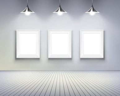 A white wall with three white blank plaques; above them are three white lights
